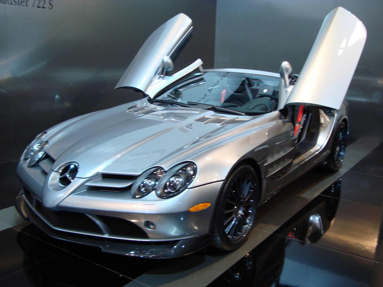 Silver roadster with upward-opening butterfly doors and sleek sporty front.