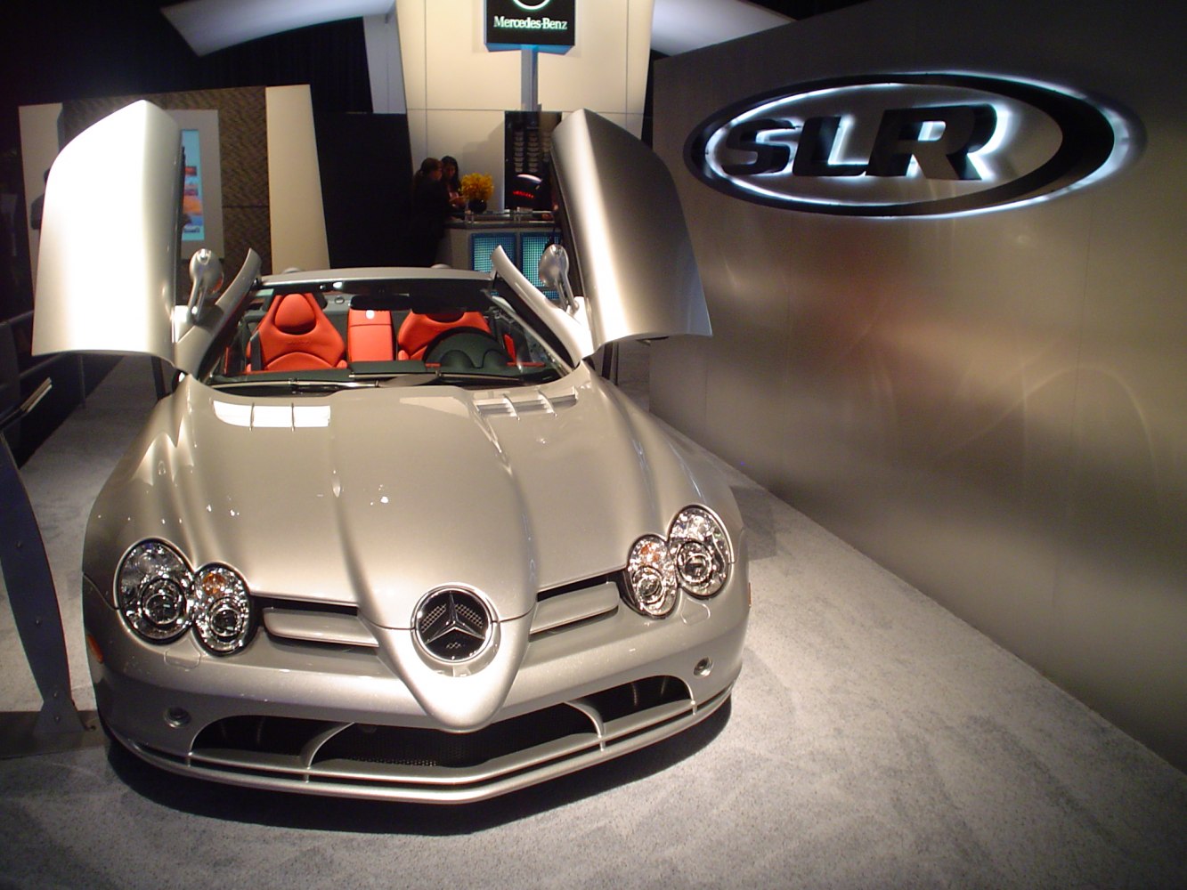 Convertible sports car with gullwing doors and dual round headlights.