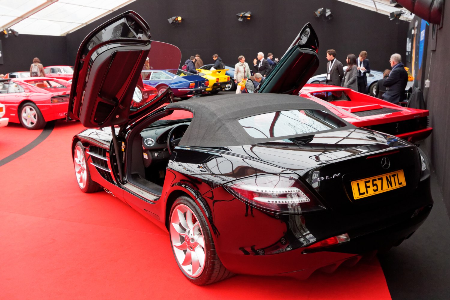 Black roadster with butterfly doors open on red floor