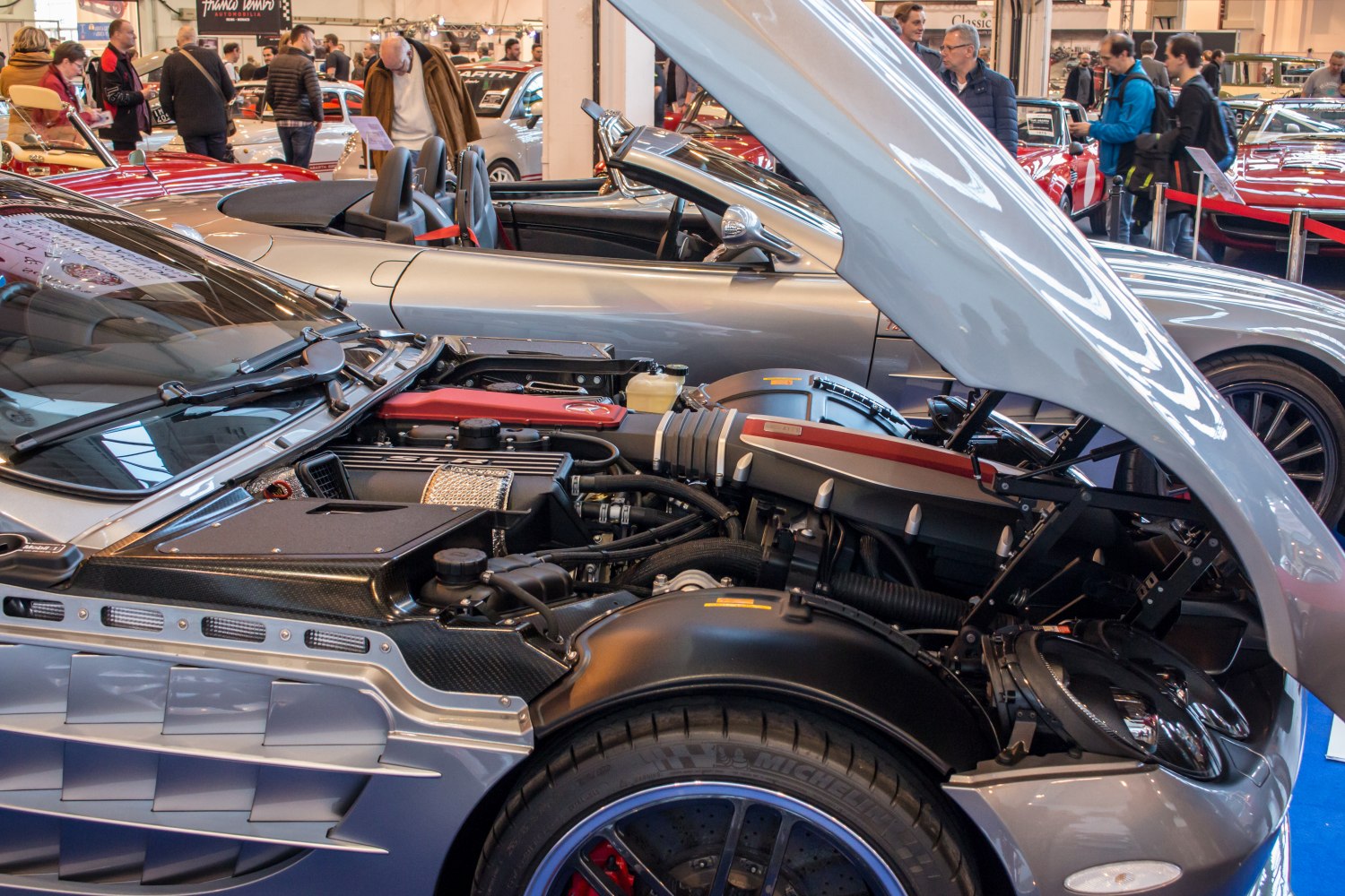 Open hood showing engine bay and side profile of a luxury roadster