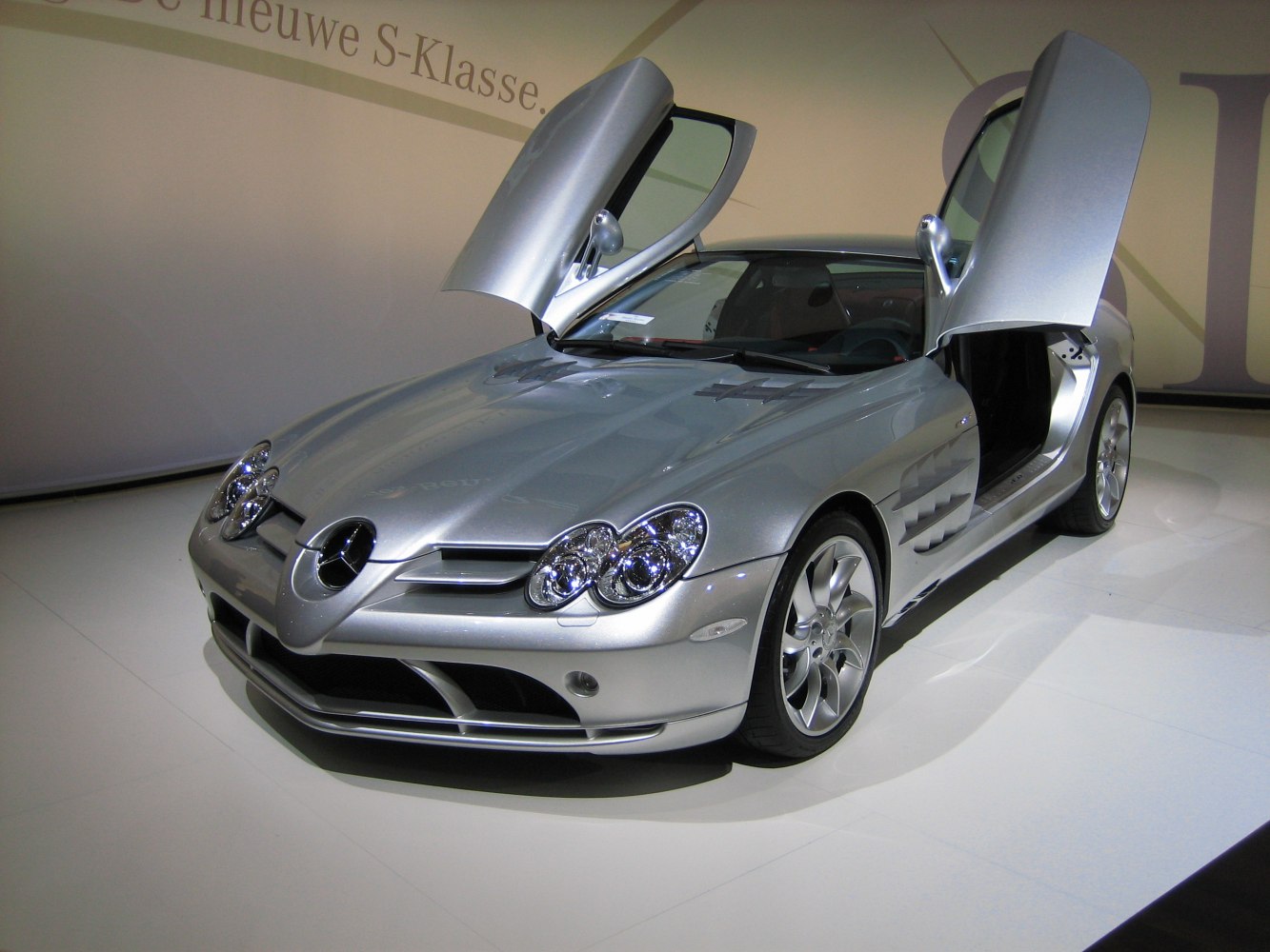 Silver coupe with distinctive gullwing doors opened.