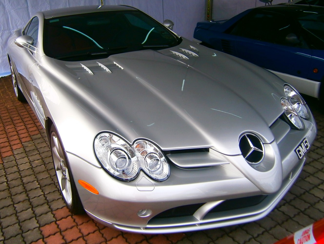 Silver luxury coupe with distinct quad headlamps and aerodynamic hood vents