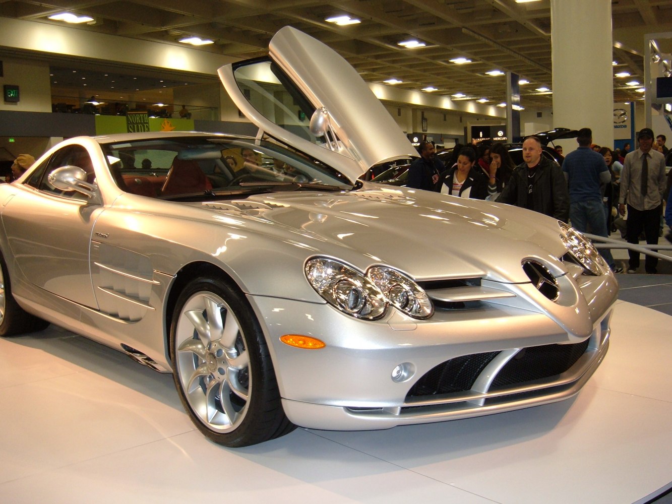 Silver luxury sports coupe with distinctive gullwing door open.