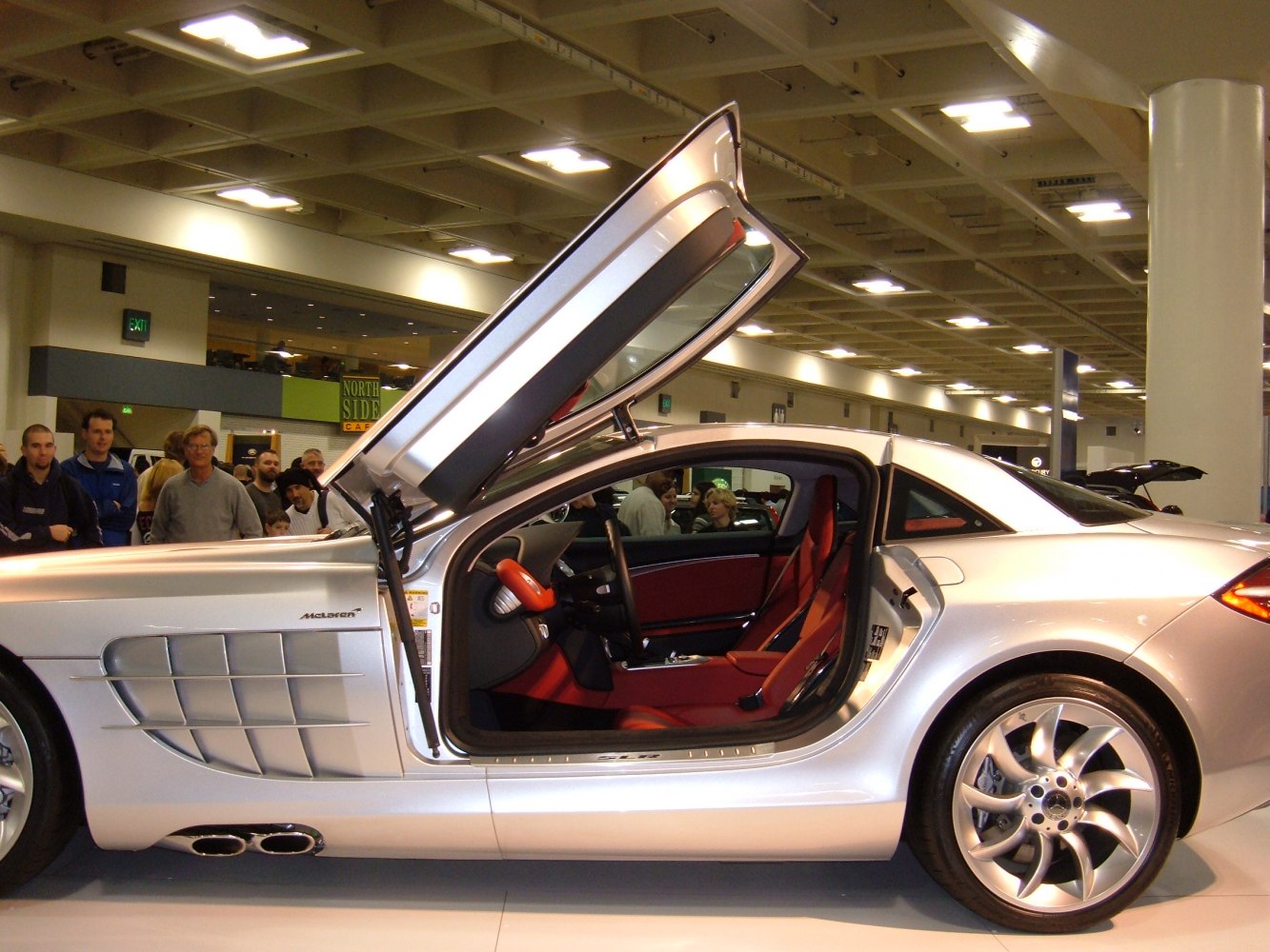Side view of coupe with gullwing door open and red interior