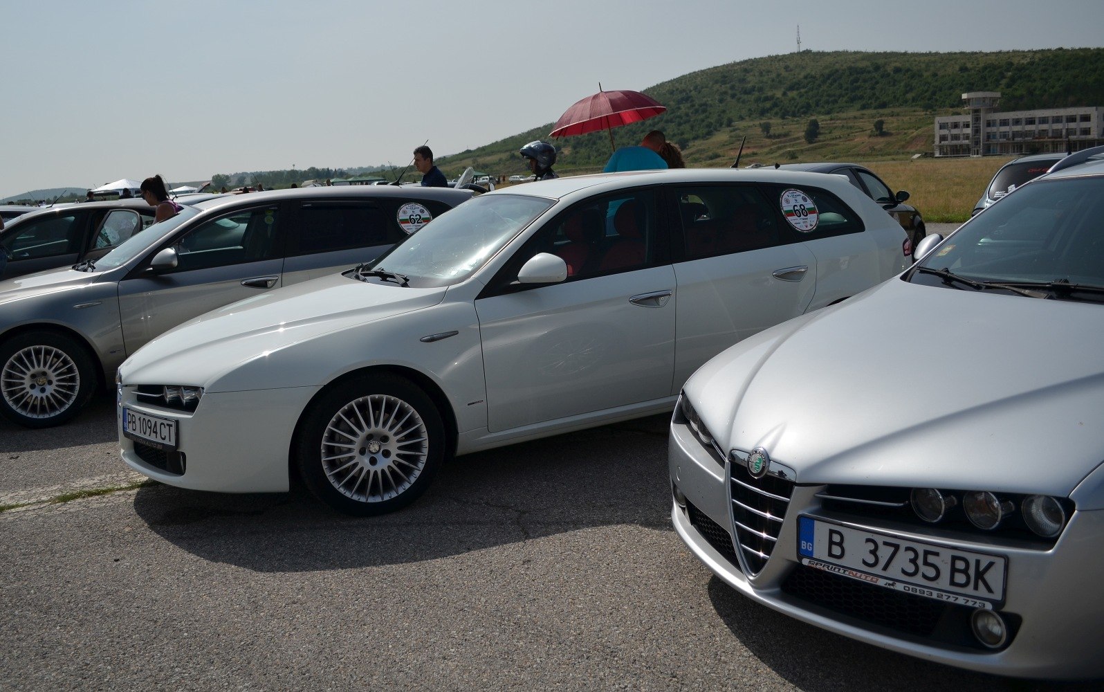 Front and side profile of a white station wagon with multi-spoke wheels