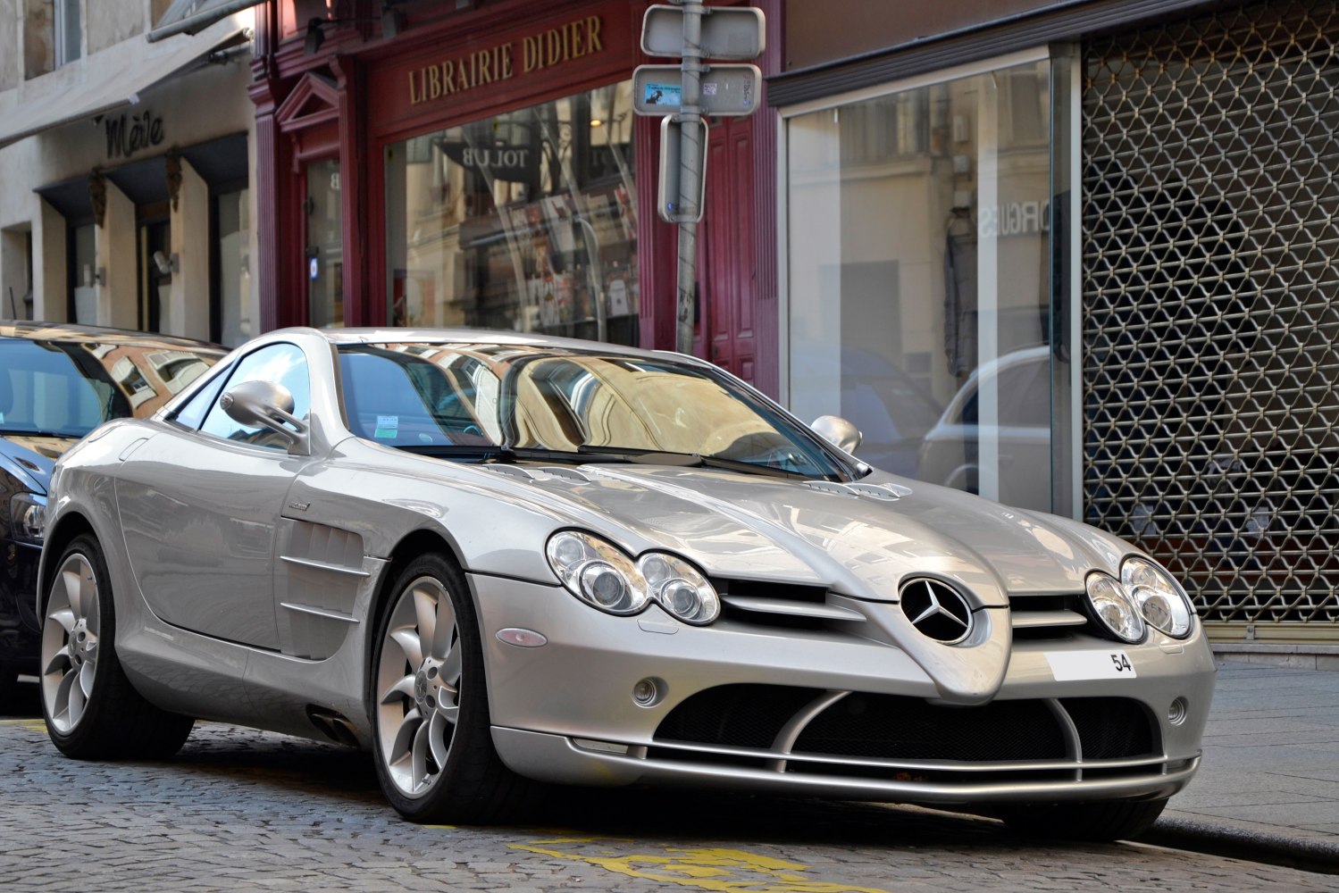 Front three-quarter view of a silver coupe with distinctive headlights and side vents.