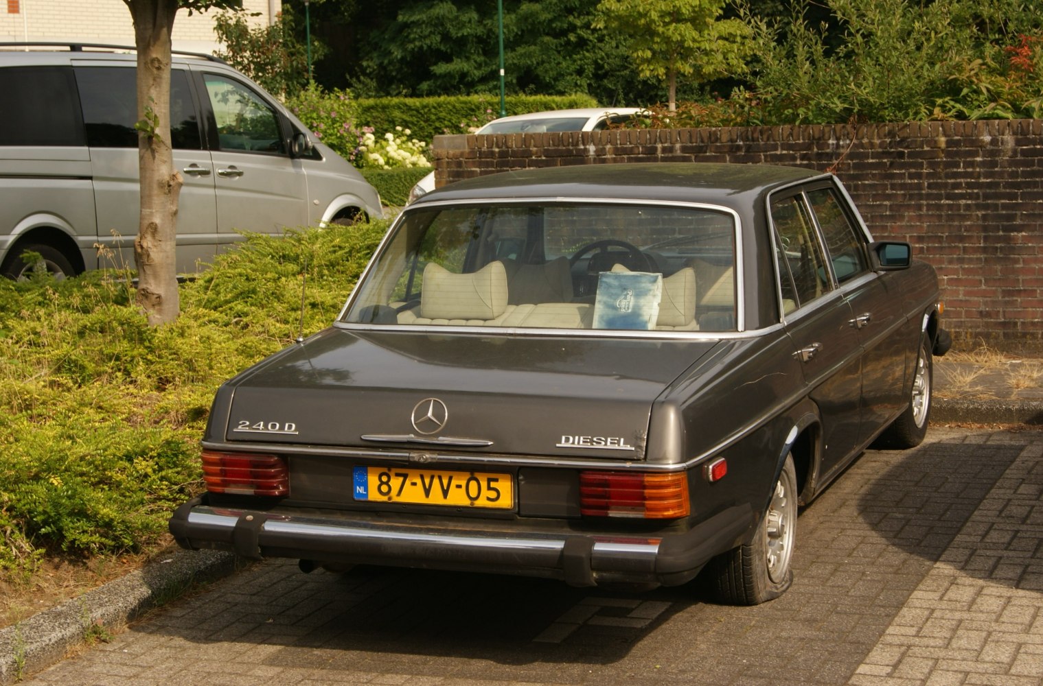 Rear view of a vintage diesel sedan with distinctive taillights and white interior seating.
