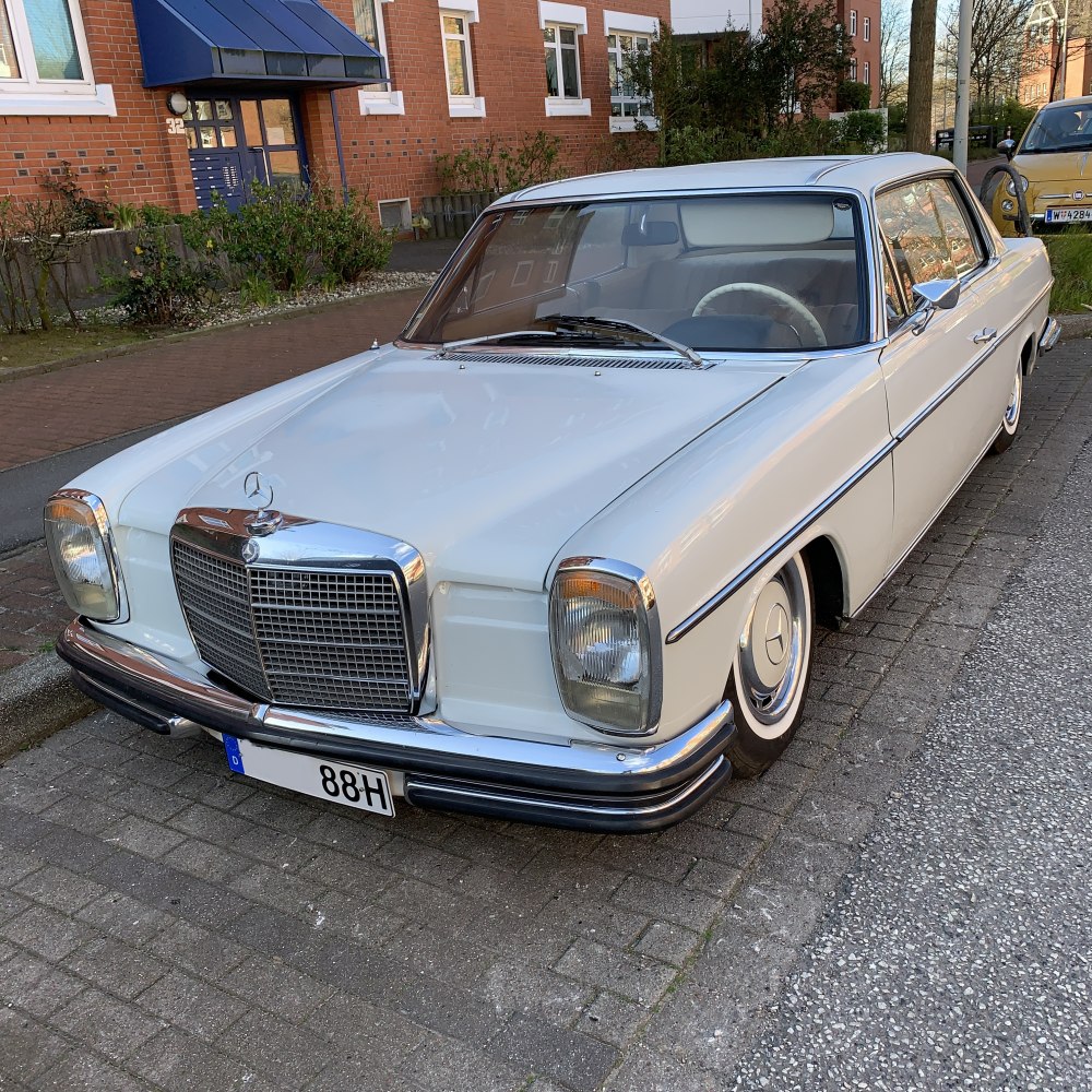 Front and side view of vintage white coupe with large chrome grille and round headlights