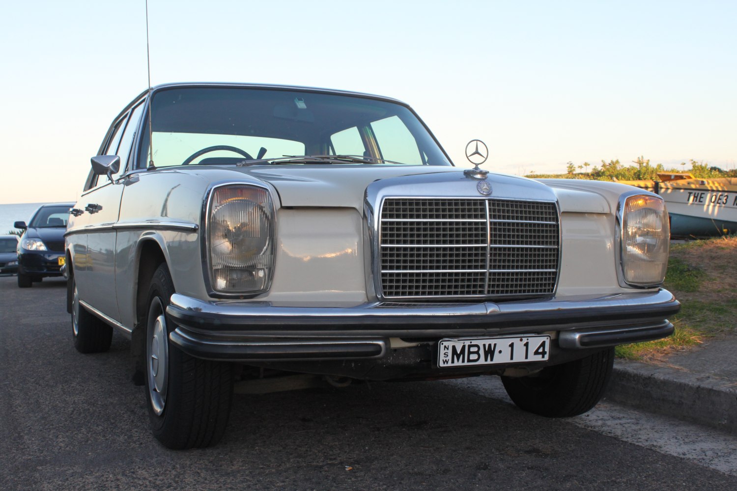 Front close-up of vintage car with rectangular headlights and large chrome grille