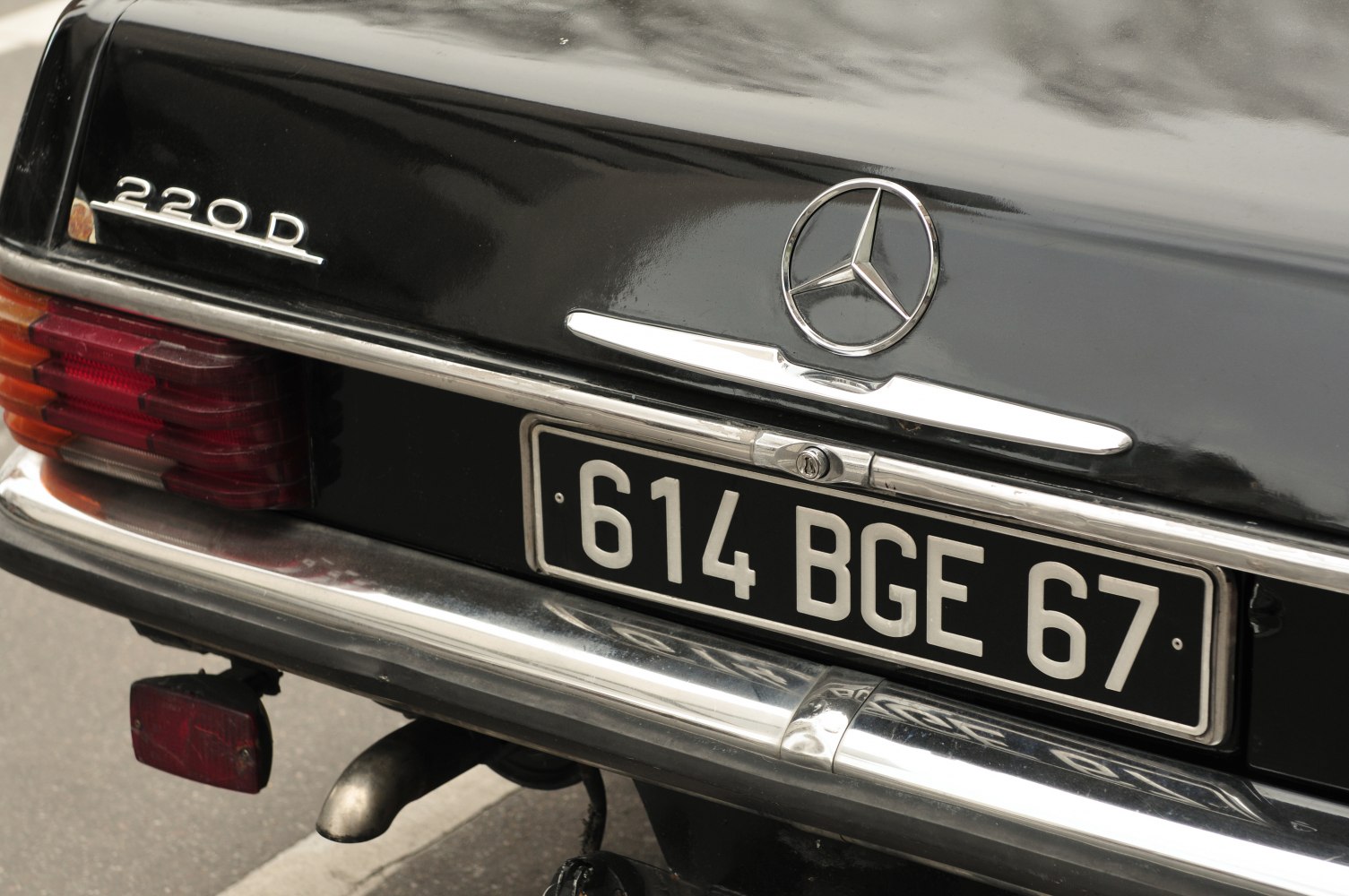 Close-up of vintage Mercedes-Benz tail light, badge, and license plate.