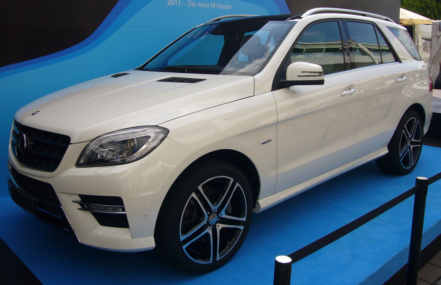 White SUV with alloy wheels, sporty hood vents, and roof rails