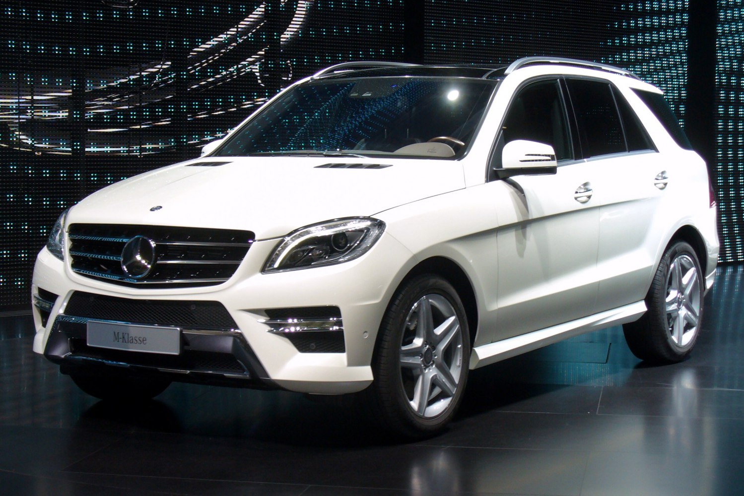 Luxury SUV front view with grille, headlights, and alloy wheels
