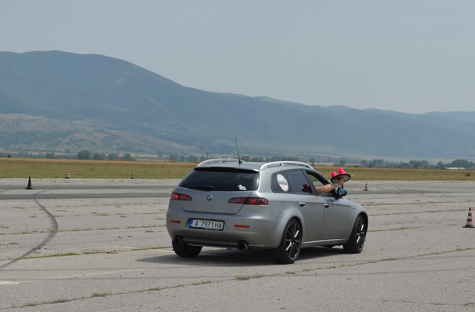 Rear view of silver sportwagon with black alloy wheels on open paved surface