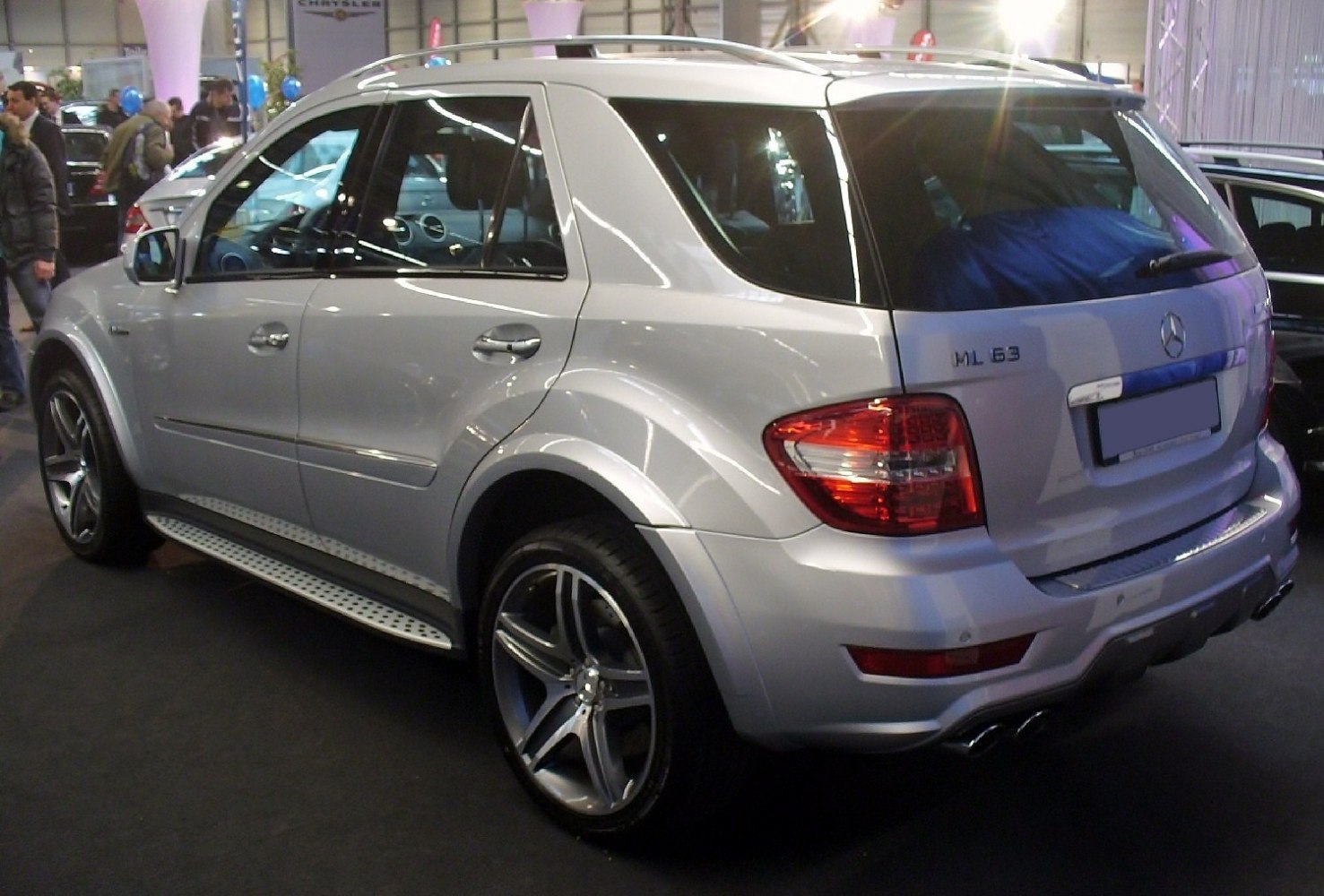 Silver midsize SUV rear-side view with AMG wheels and dual exhaust