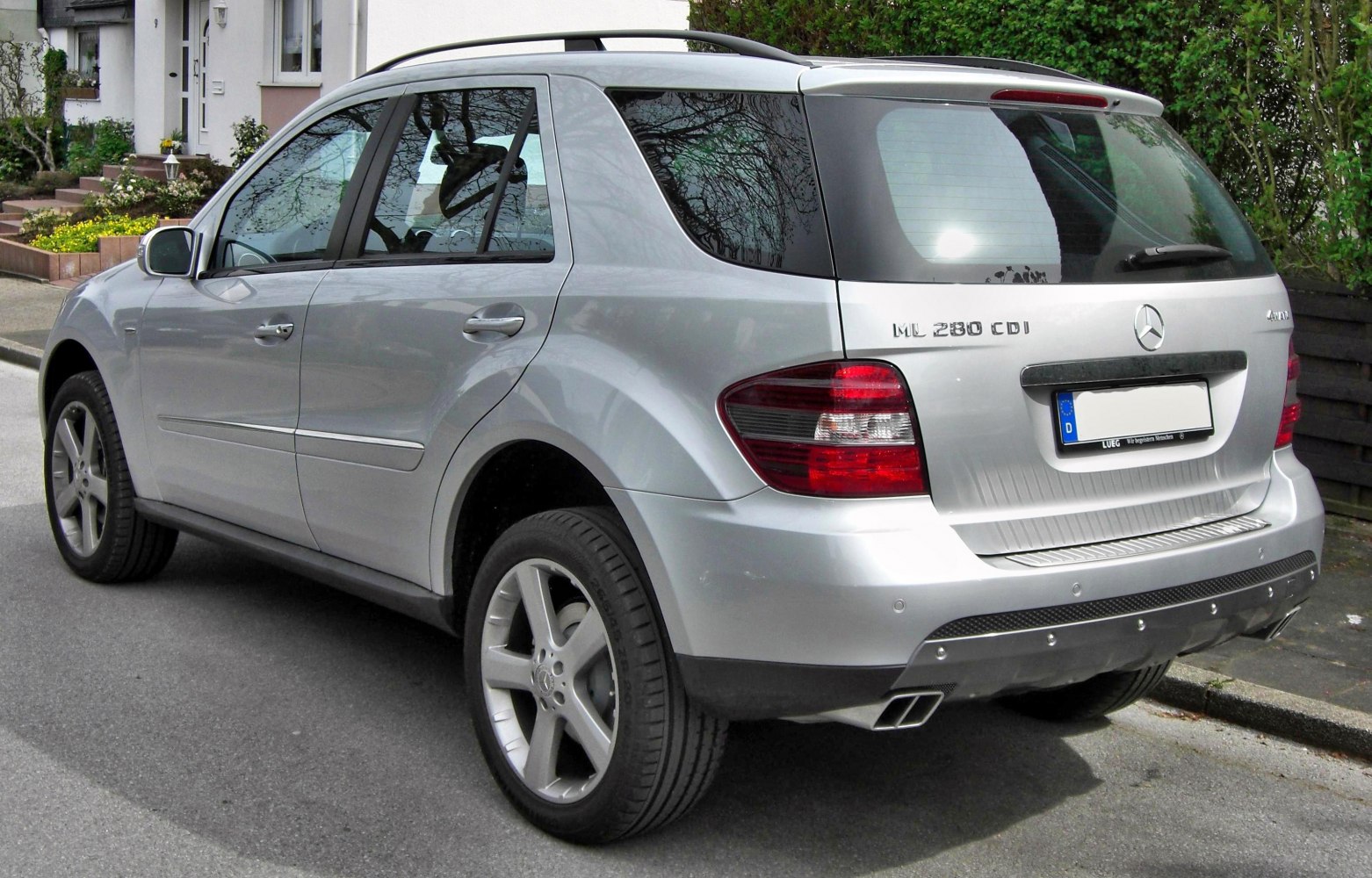 Rear side view of a silver SUV with dual exhaust and distinct tail lights