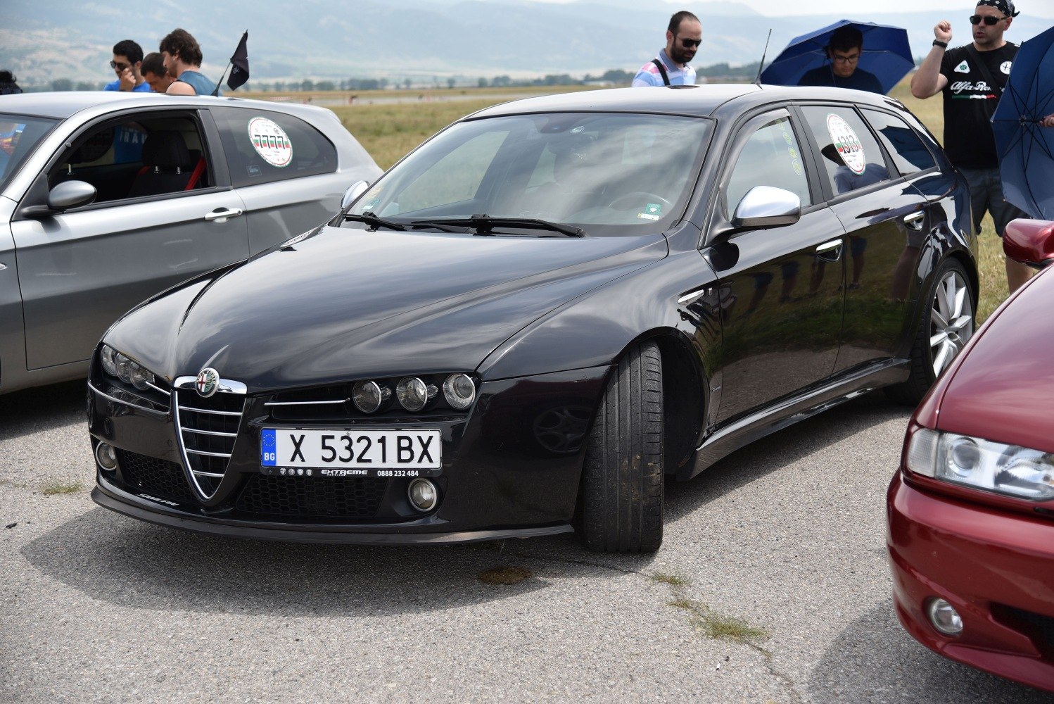 Front view of a black wagon with triple round headlights and Alfa grille.