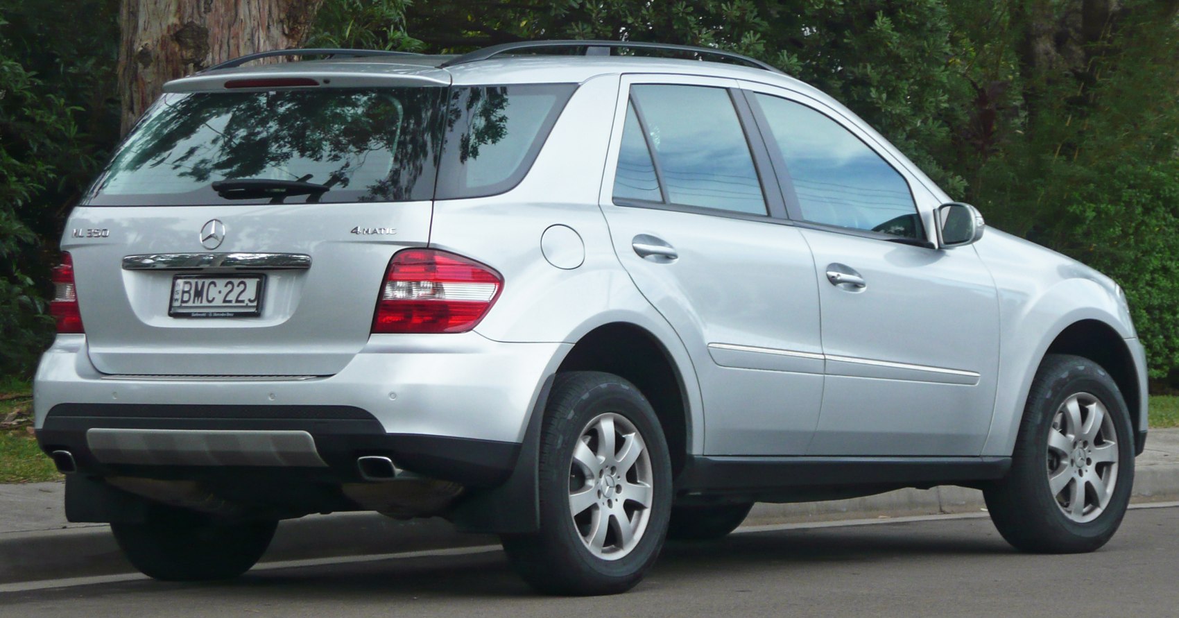 Silver SUV rear with dual exhausts, roof rails, large taillights