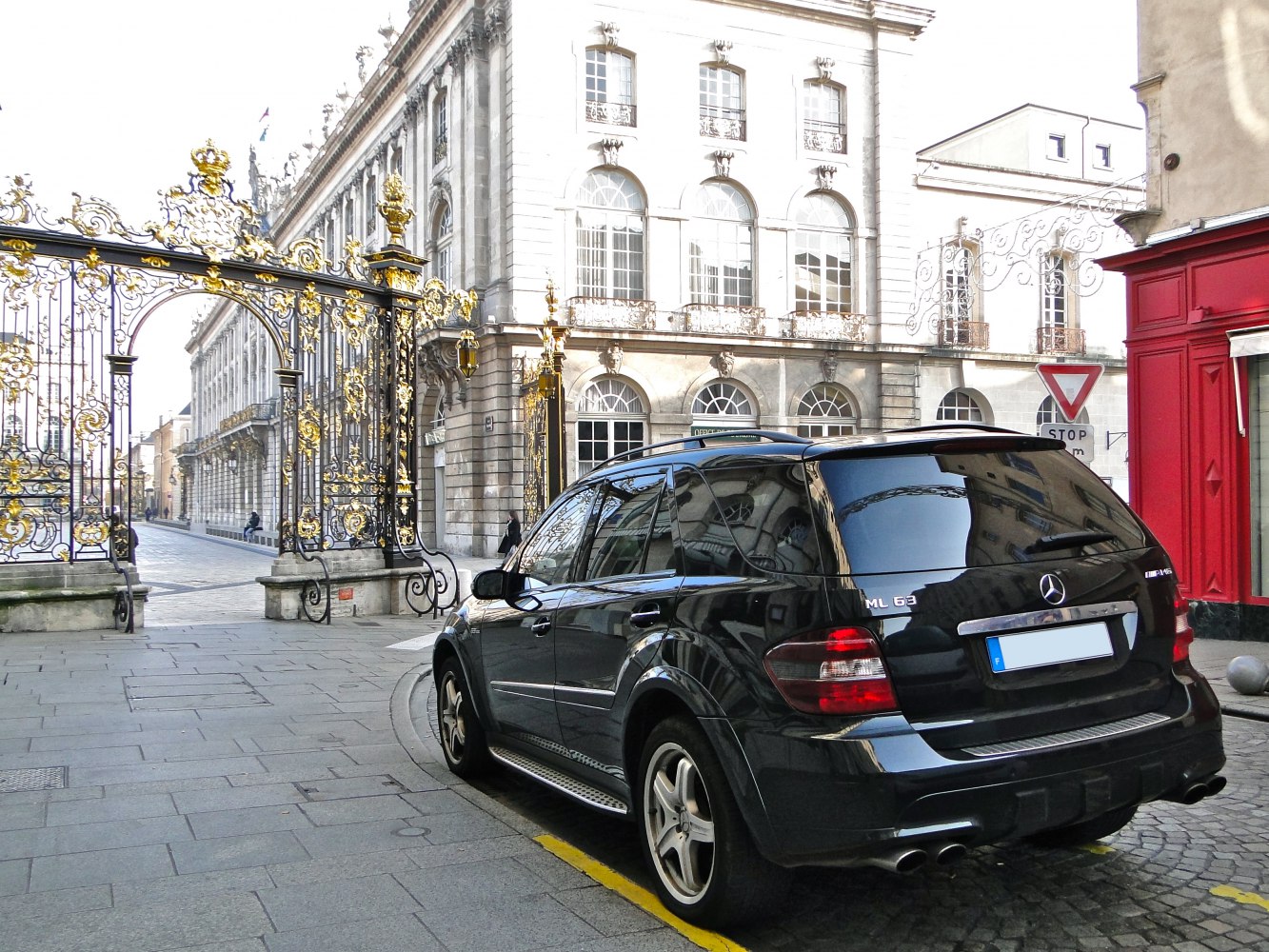 Rear view of black SUV with quad exhausts and tinted windows parked by ornate gates