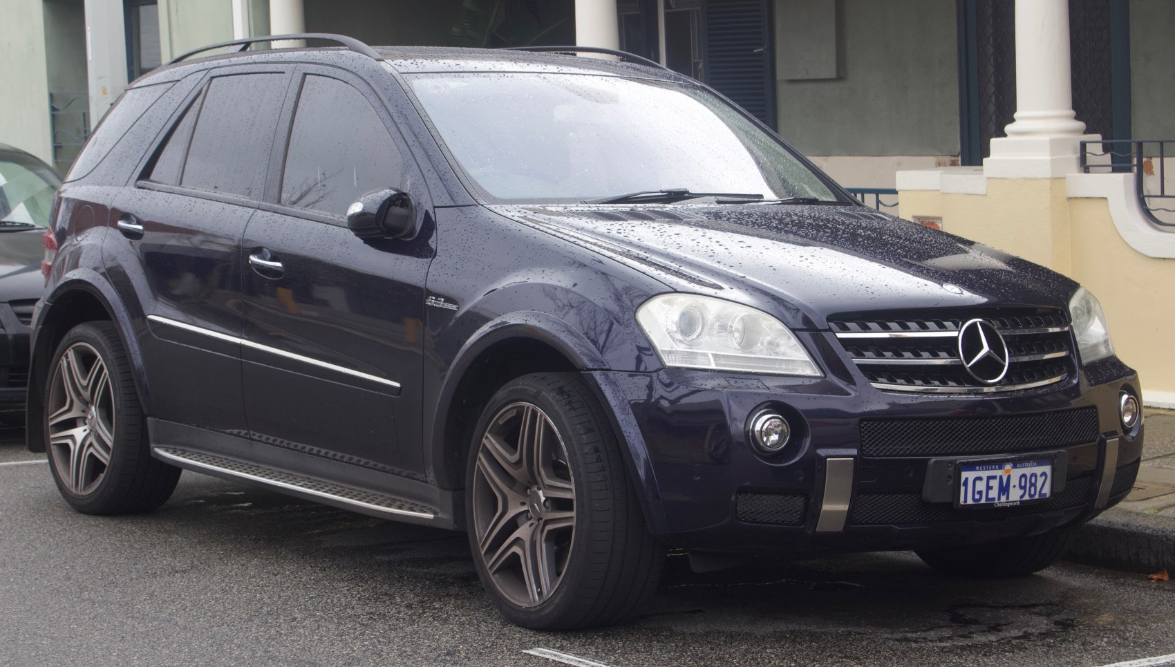 Front side view of a wet SUV with distinctive grille and alloy wheels