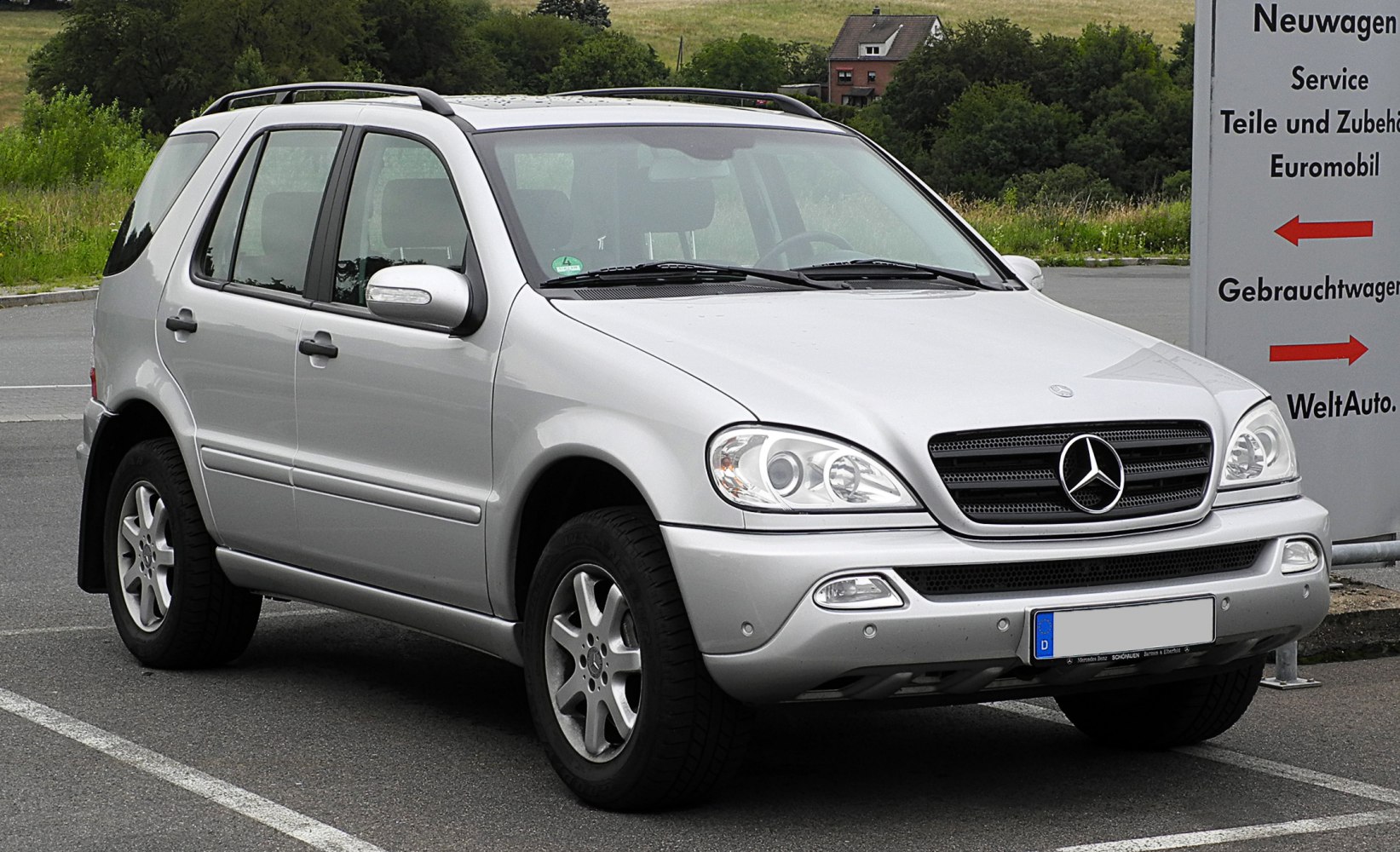 Silver SUV with large grille, dual headlights, fog lights, and roof rails