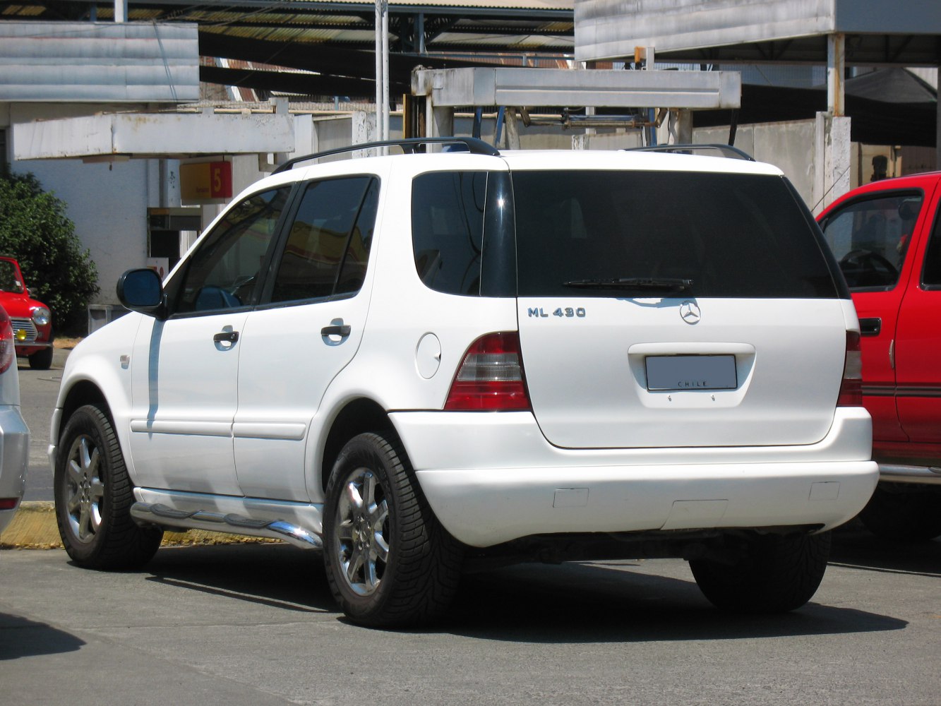 Rear side view of white SUV with chrome wheels and roof rails