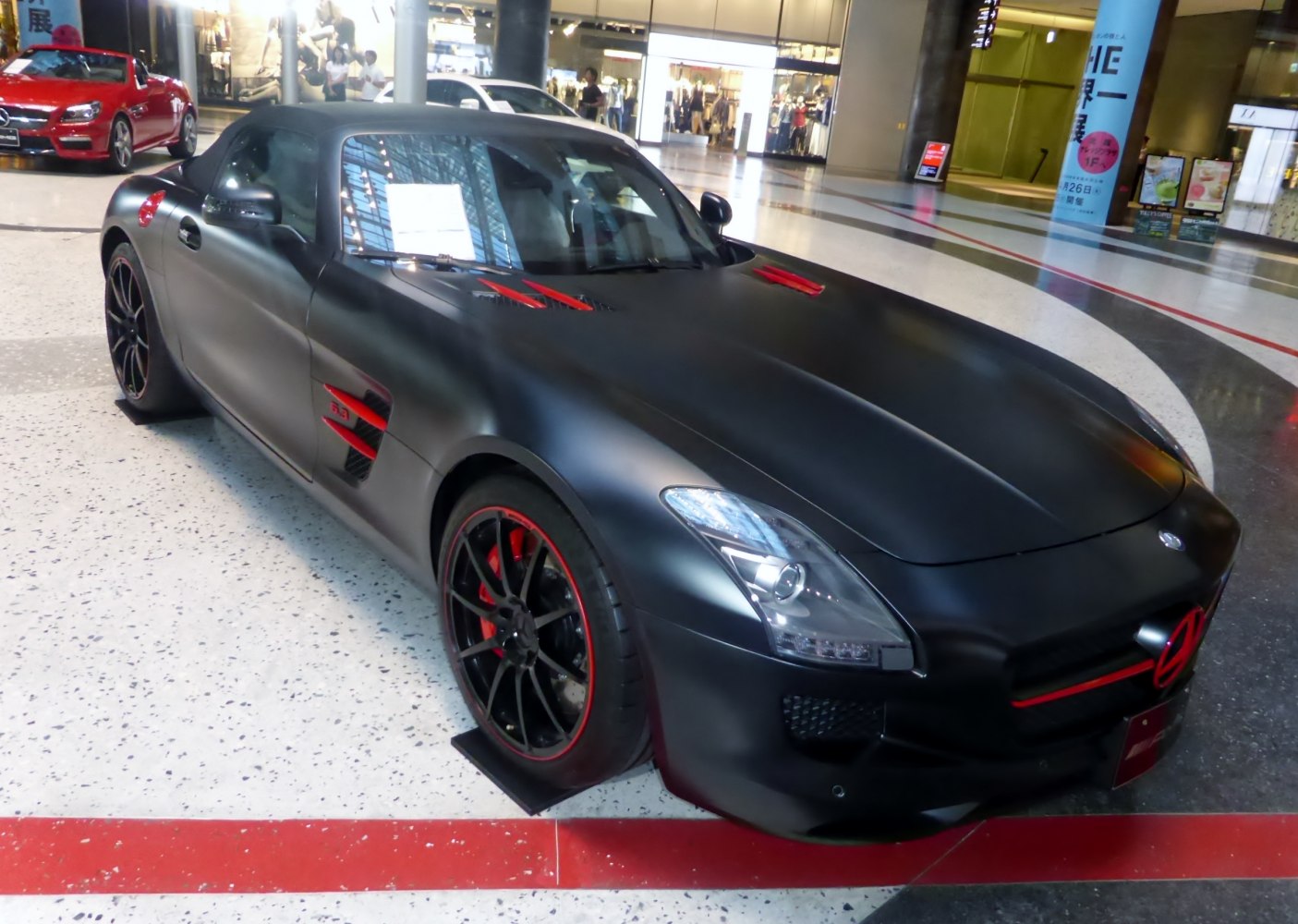 Matte black roadster with red accents on grille, hood, and wheels.