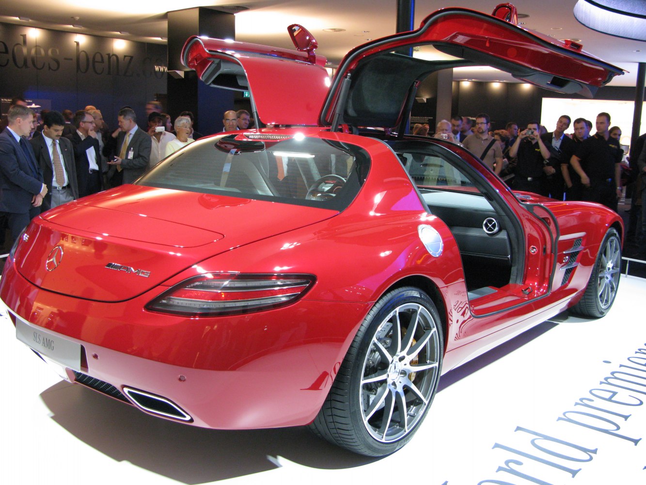 Red sports coupe with distinctive gullwing doors and AMG badge rear