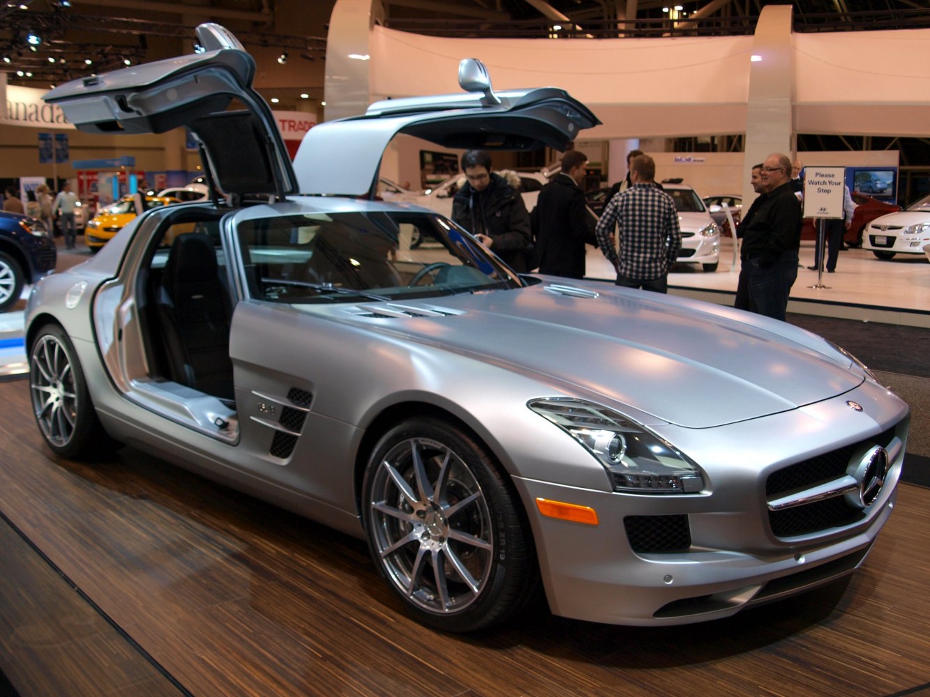 Silver sports coupe with iconic gullwing doors open, detailed front design