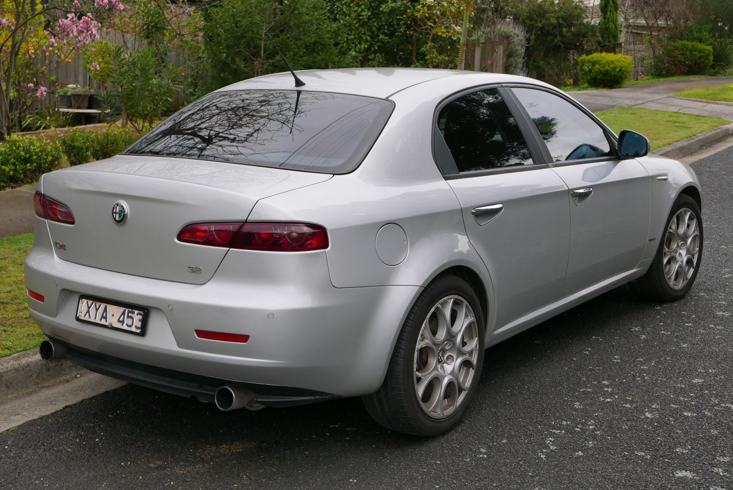 Silver sedan rear side with round taillights and sporty alloy wheels