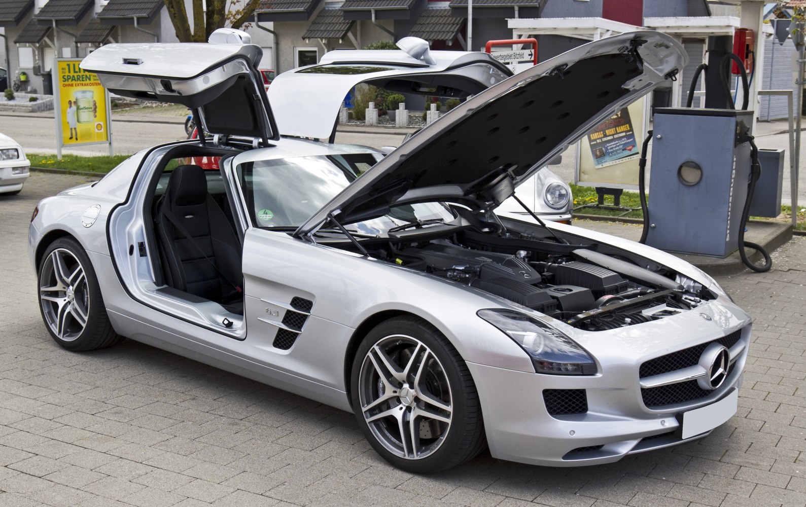 Silver sports coupe with gullwing doors and open engine bay.