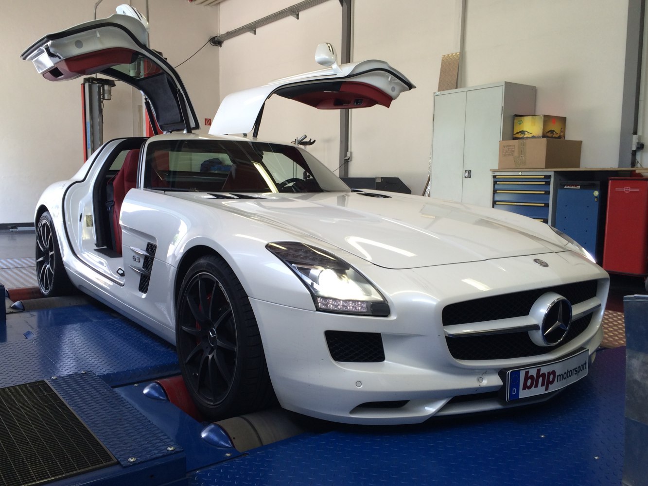 White coupe with iconic gullwing doors open and LED headlights lit