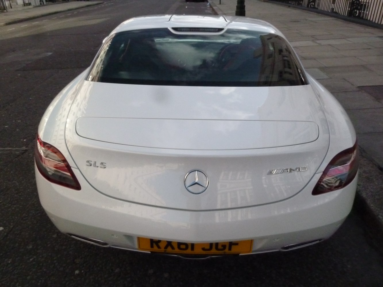 Rear view of a white luxury coupe with distinctive AMG badge and sleek taillights