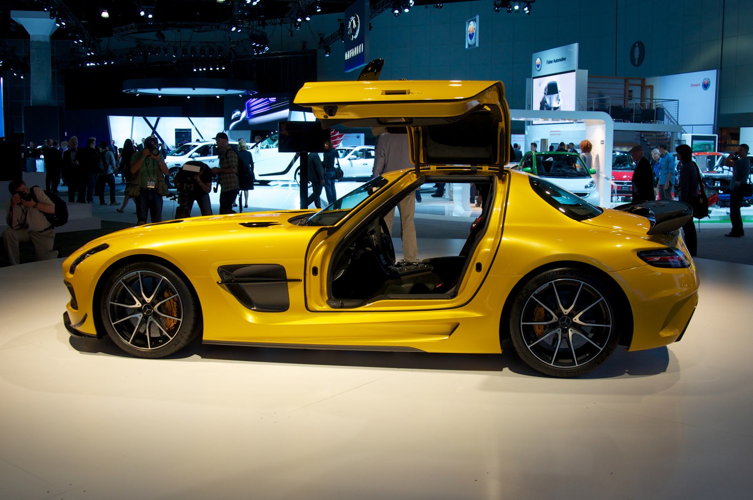 Yellow coupe with distinctive gullwing doors open, sporty aerodynamic styling.