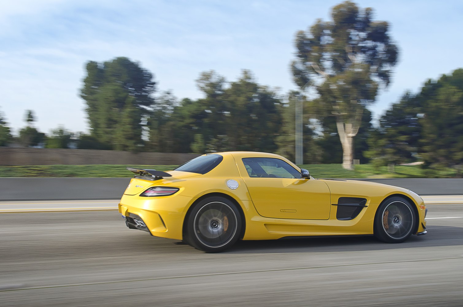 Yellow sports coupe with rear spoiler in motion, side profile