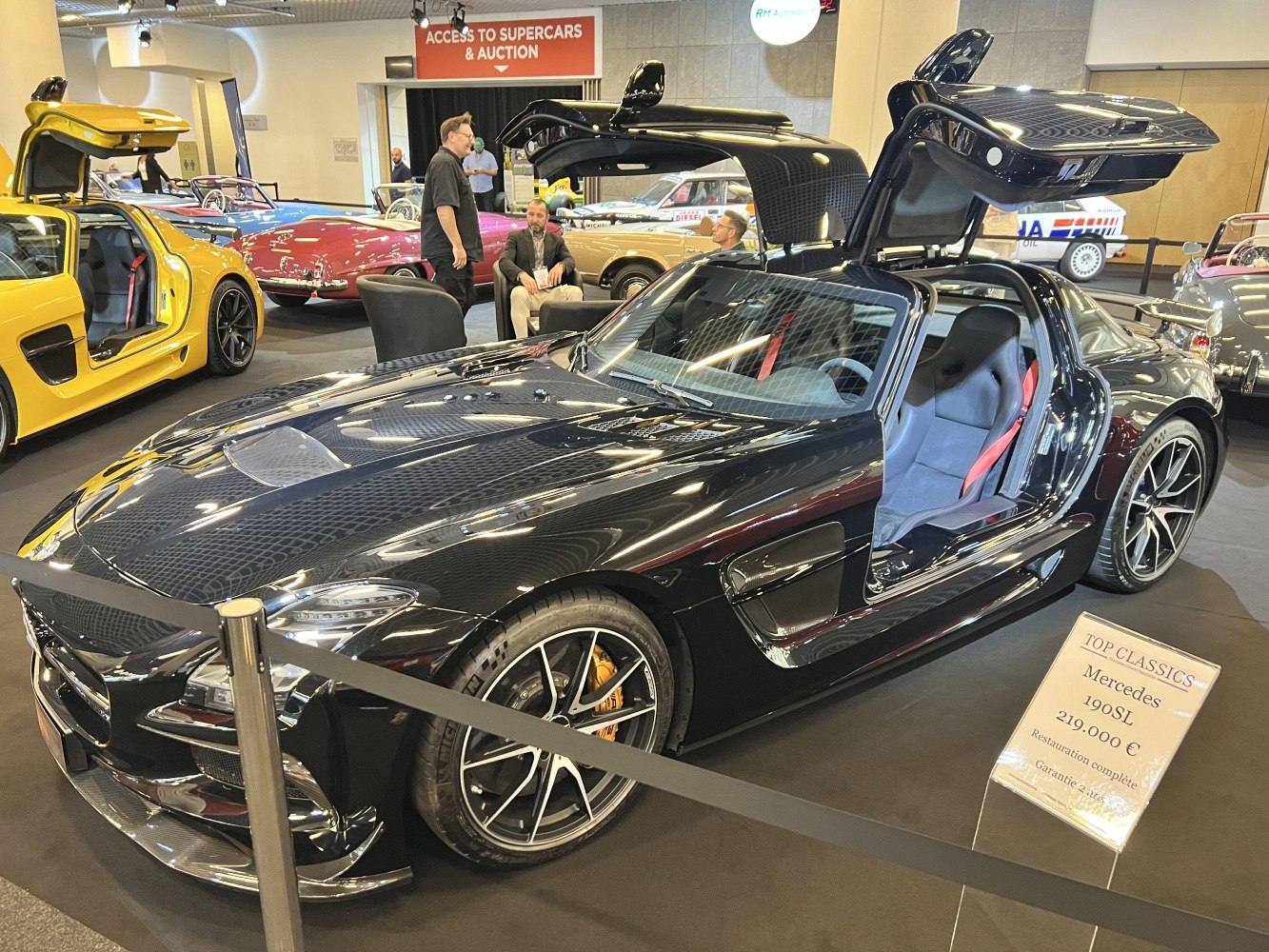 Black sports coupe with iconic gullwing doors open and AMG wheels
