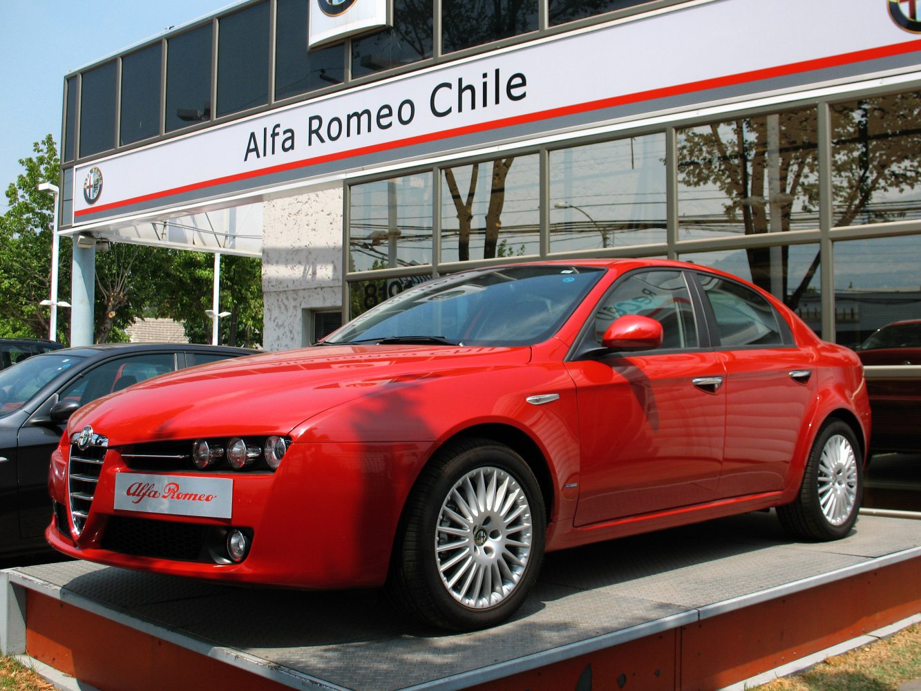Red sedan with distinctive grille and triple headlights, front side view
