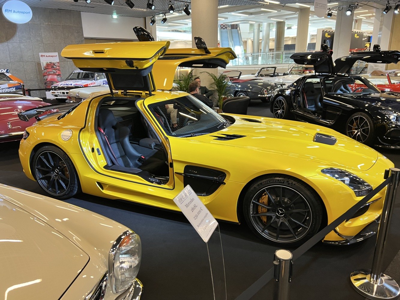 Yellow sports coupe with open gullwing doors and black alloy wheels