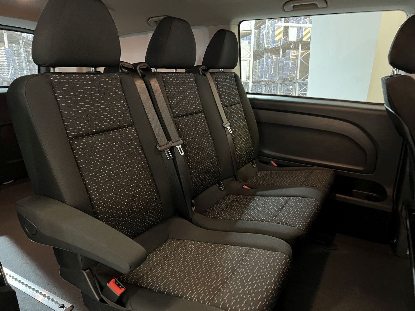 Rear passenger seats with headrests and seat belts in a van interior