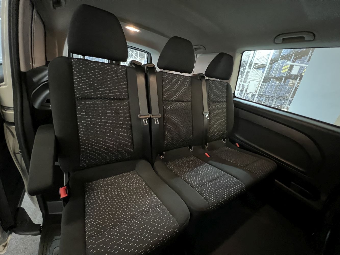 Rear passenger seats with fabric upholstery, headrests, and seat belts.