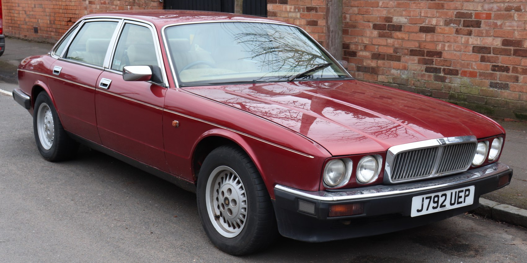 Red four-door sedan with quad round headlights and prominent chrome grille