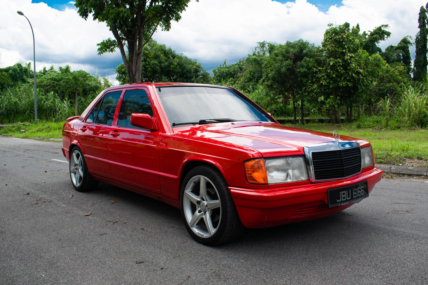Red 1980s sedan with chrome front grille and five-spoke alloy wheels