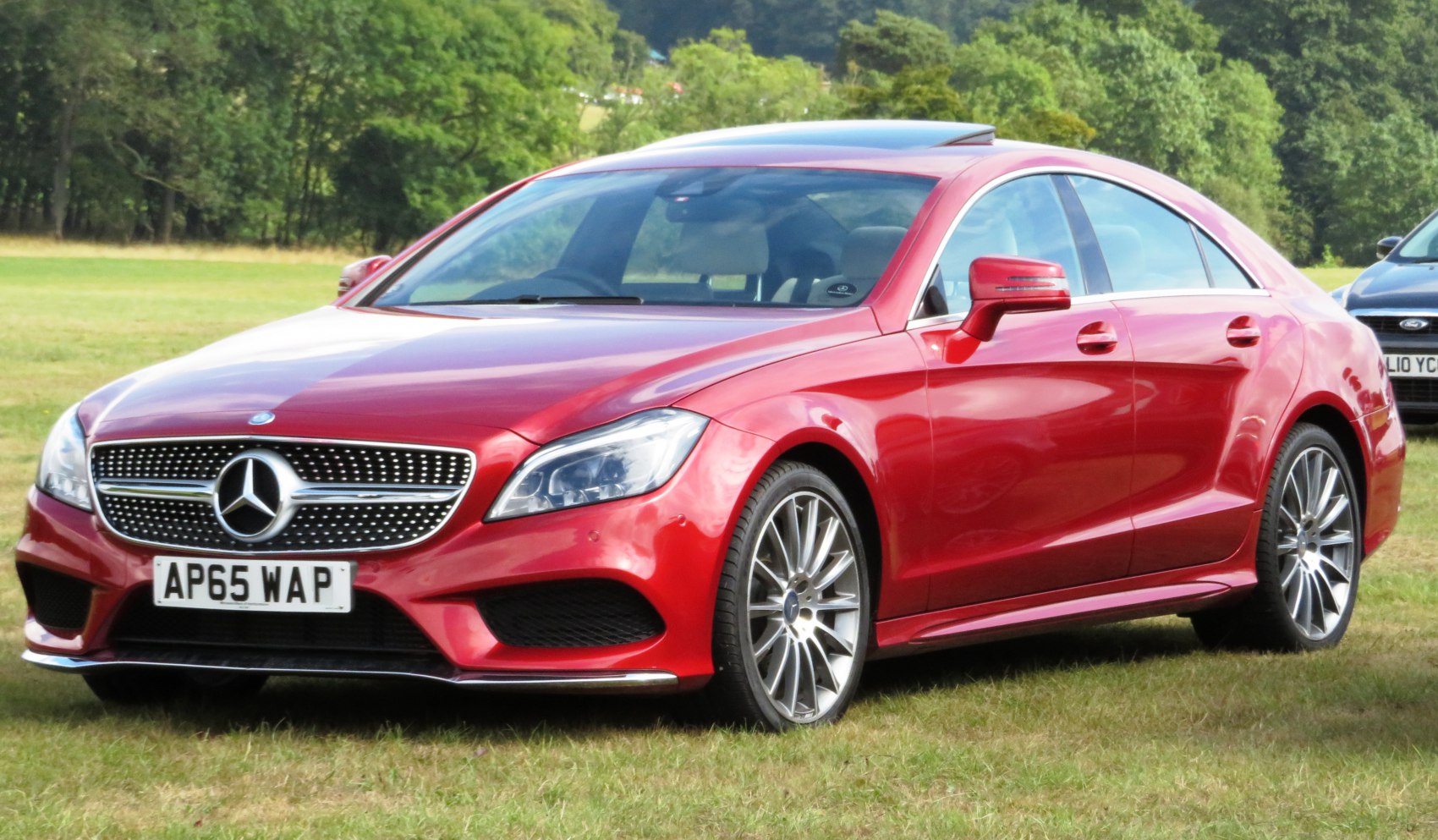 Front-side view of red luxury coupe with distinctive grille and alloy wheels
