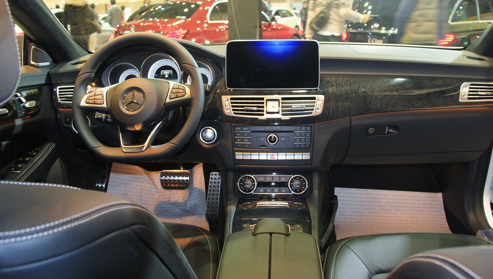 Luxury car interior with wood trim, digital display, and leather steering wheel