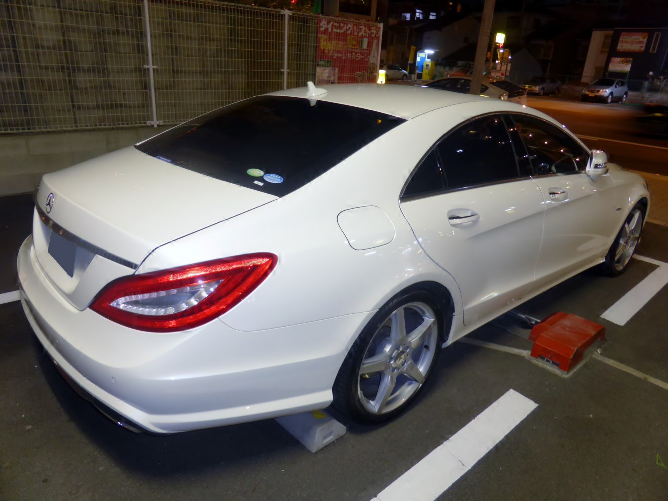 Rear three-quarter view of white luxury sedan with LED taillights and alloy wheels at night