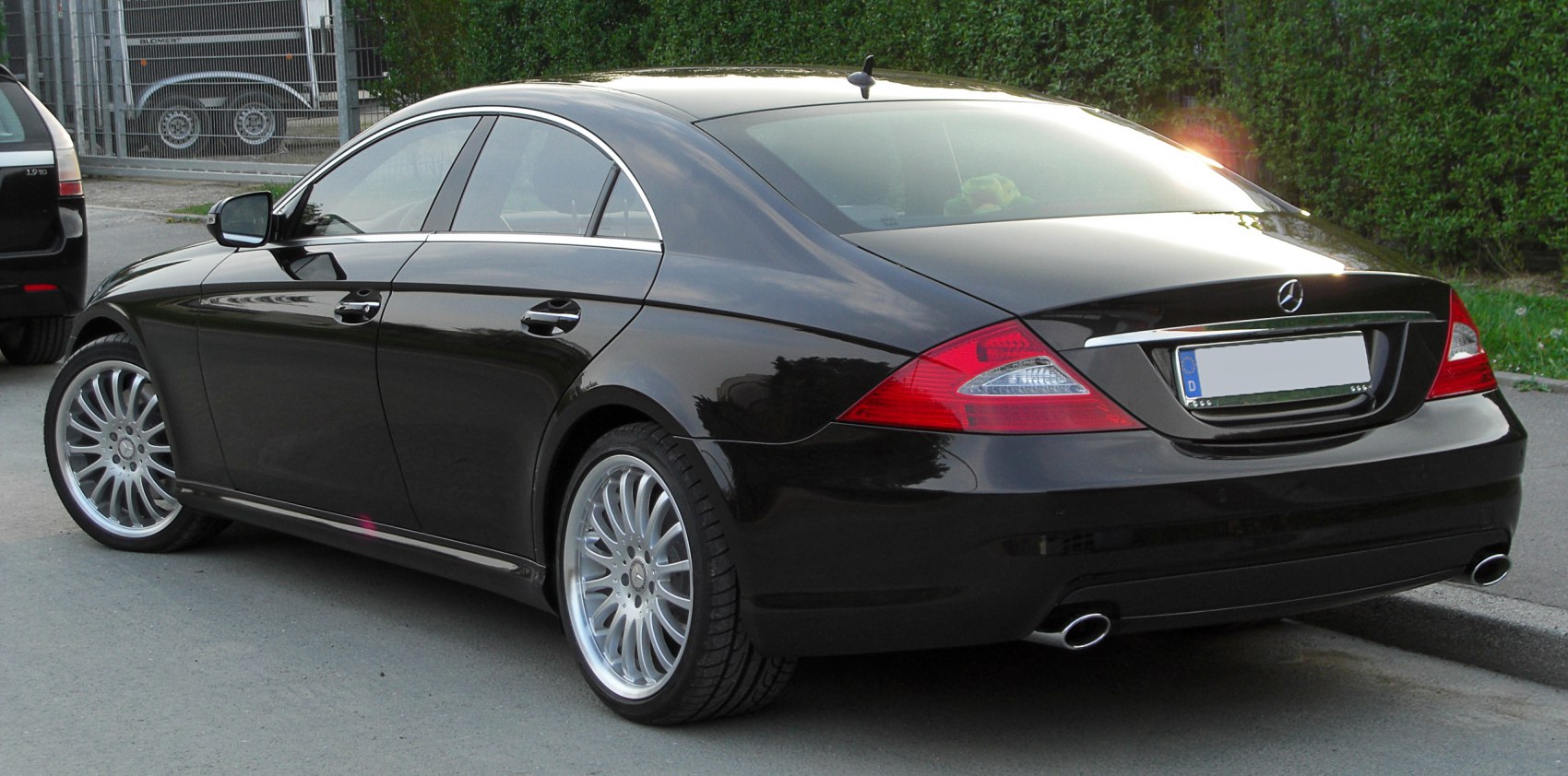 Sleek black luxury sedan rear side with alloy wheels and dual exhausts