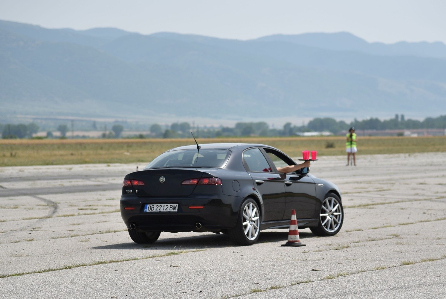 Rear side view of black sedan with sporty wheels and traffic cone