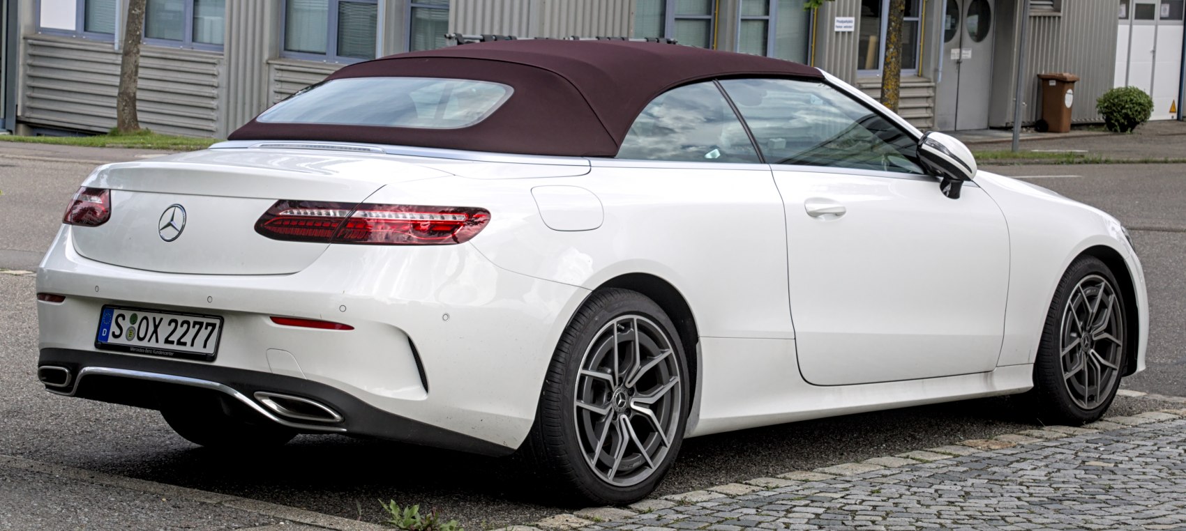 Rear-side view of a luxury convertible with fabric soft top and alloy wheels
