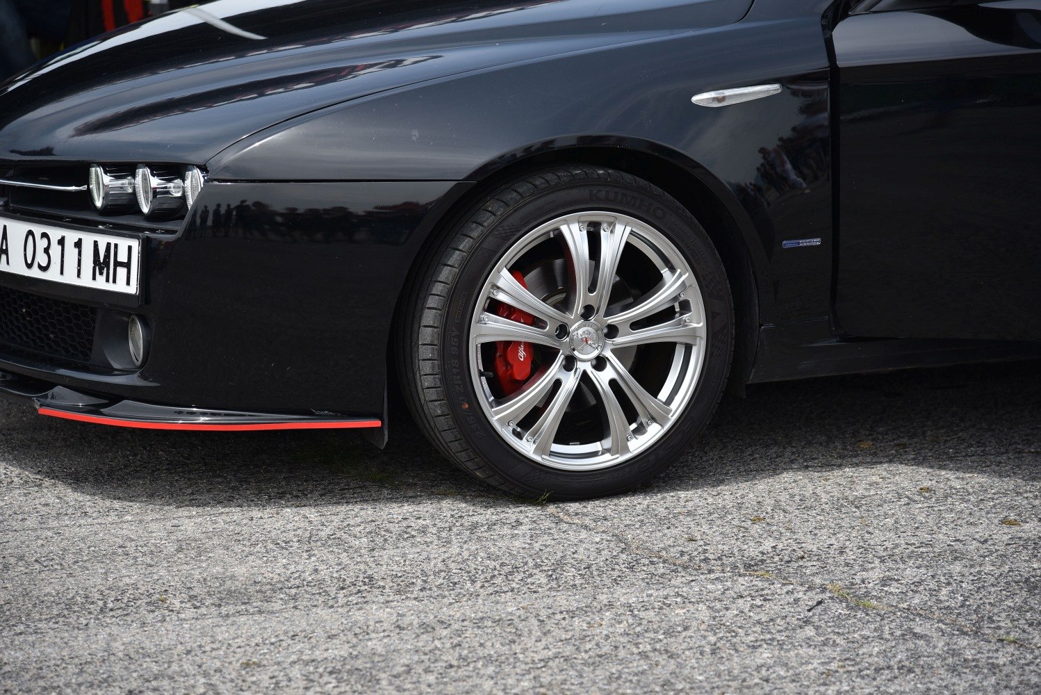 Close-up of front alloy wheel with red brake caliper and front fender details