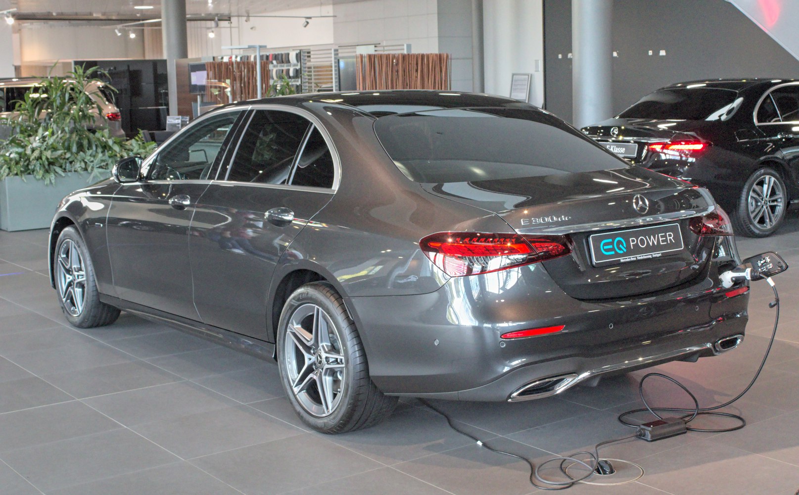 Rear side view of a plug-in hybrid sedan with charging cable connected