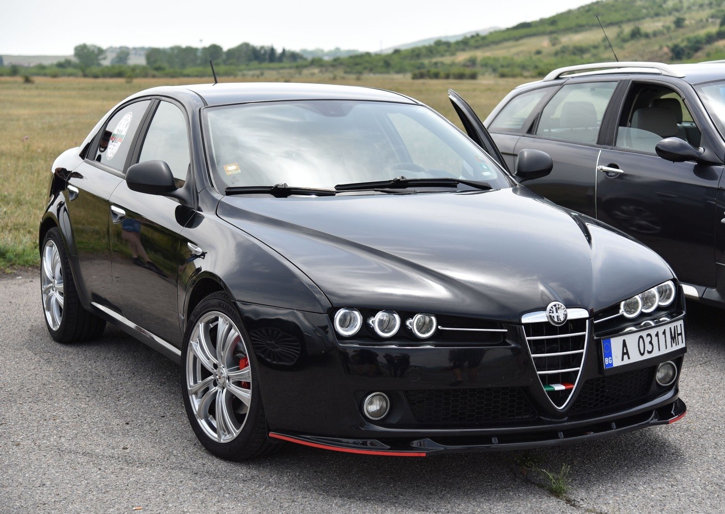 Triple round headlights and V-shaped grille on black sedan front